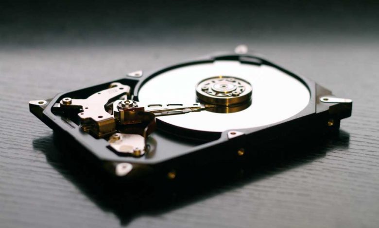 Hard drive with platter exposed, on a dark wood table
