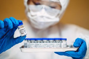 A researcher holds a tray of COVID-19 vaccines.
