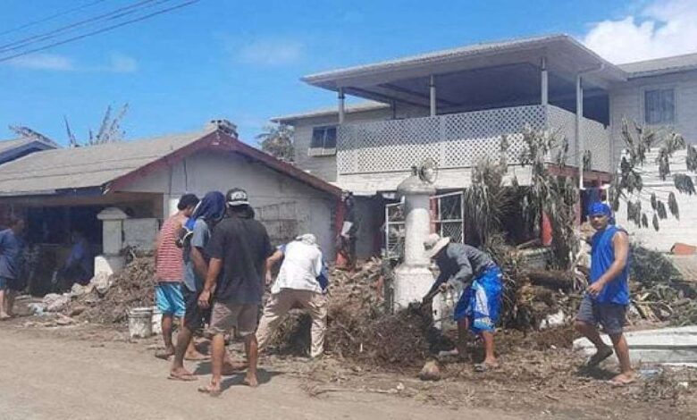 People clean debris following volcanic eruption and tsunami, in Nuku'alofa, Tonga on Tuesday in this picture obtained from social media on Wednesday.