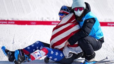 Jessie Diggins is helped off the course after winning the silver medal in the women’s cross-country skiing 30K at the 2022 Beijing Olympics.