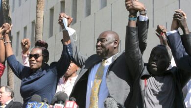 Attorney Benjamin Crump holds up the arms of Ahmaud Arbery's parents, Wanda Cooper-Jones and Marcus Arbery, on Tuesday, Feb. 22, 2022, outside the federal courthouse in Brunswick, Georgia. The three men convicted of Ahmaud Arbery’s murder were also found guilty of federal hate crimes.