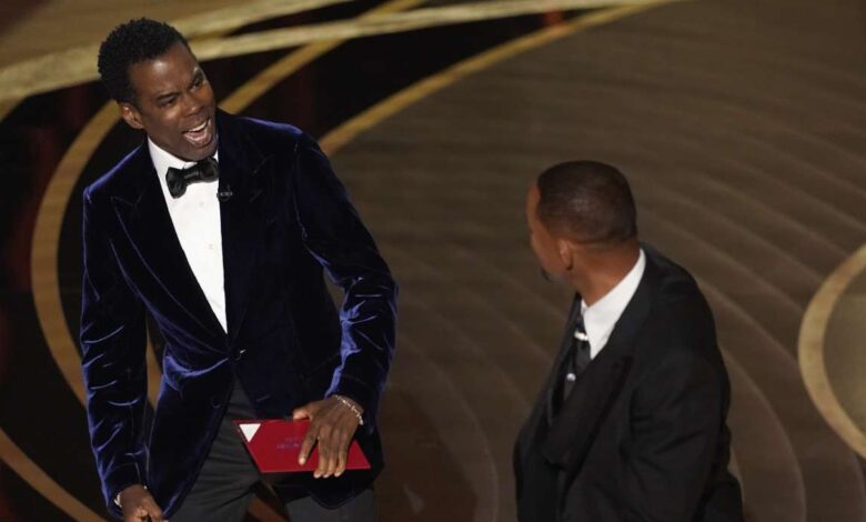 Presenter Chris Rock, left, reacts after being hit on stage by Will Smith while presenting the award for best documentary feature at the Oscars on Sunday, at the Dolby Theatre in Los Angeles.